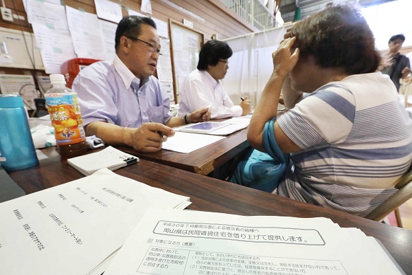 「みなし仮設住宅」の相談窓口で話を聞く被災者（写真：時事通信フォト）