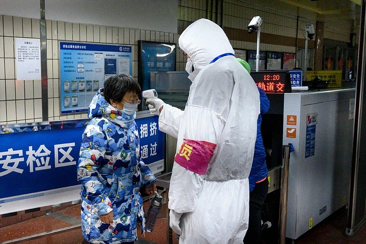 北京の地下鉄入り口で防護服姿の保安要員から検温を受ける乗客（AFP＝時事）