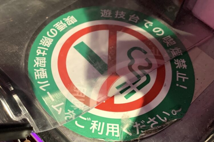 かつて灰皿が置いてあったパチンコ台の横には禁煙化を告知するステッカーが貼ってある