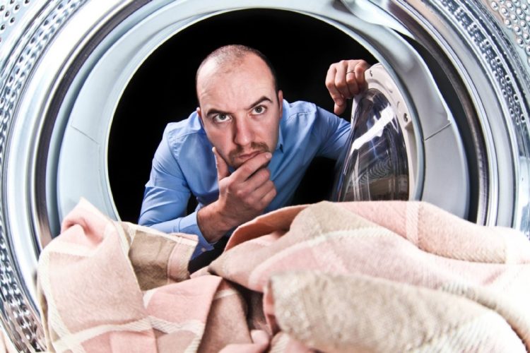 「こんなはずじゃないんだが」ドラム式洗濯機の中を除く男性（イメージ。写真：アフロ）