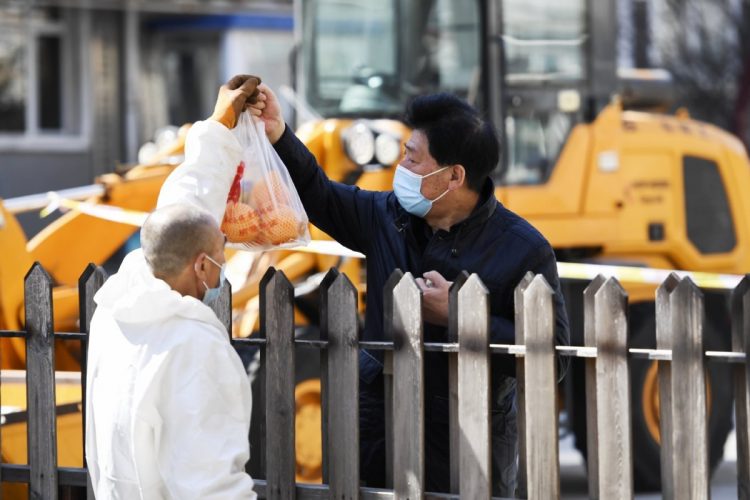 塀越しにデリバリーした食材を受け取る男性（吉林省長春市。Getty Images）