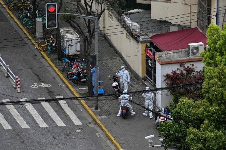 ロックダウン（都市封鎖）中の上海で、路上に立つ防護服を着た警察官（AFP=時事）