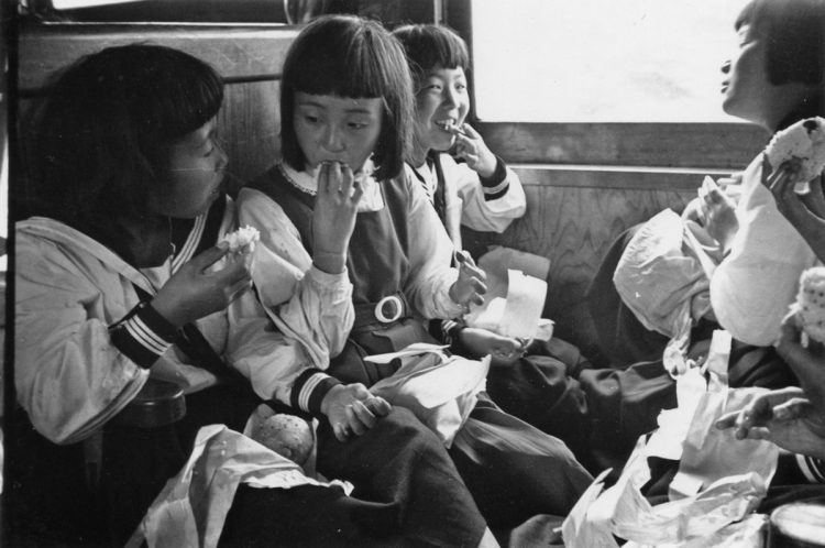 昭和30年の小学生の遠足時、車内で直角椅子に座ってお弁当を食べているひとコマ（写真提供／鉄道博物館）