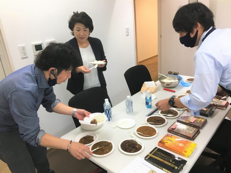 レトルトカレーの開発にあたり、試作品と他社のレトルトカレーを食べ比べ。社員と一緒に自ら市場調査を行う