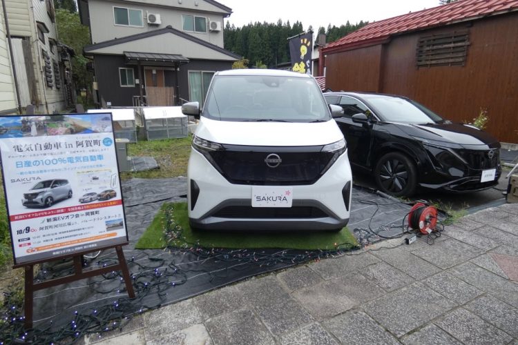 行列が通る街道脇に展示されたサクラとアリアで、電源車としてのEVをアピール