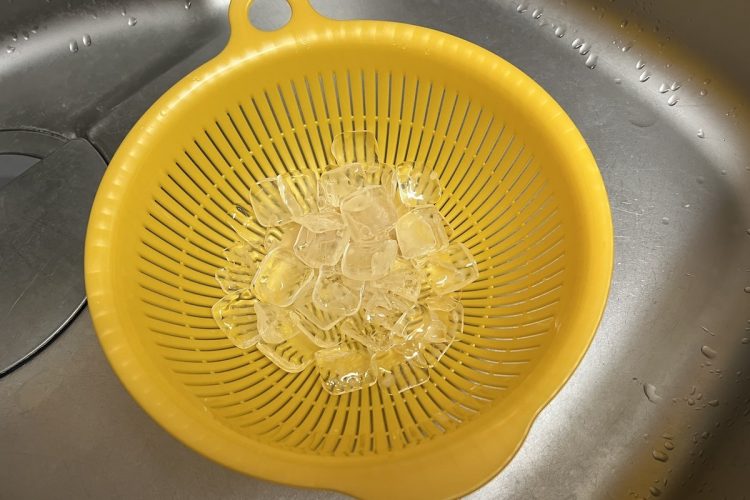 コンビニで買ったカフェオレの氷をザルにあげて洗う
