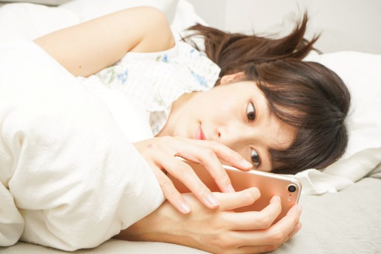 大学をサボった日はほぼ一日中ベッドでスマホいじり(写真:イメージマート)