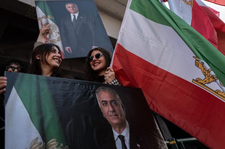 イラン王朝時代の国旗と元皇太子の肖像を掲げ、米・イスラエルの攻撃を支持する人々（AFP=時事）