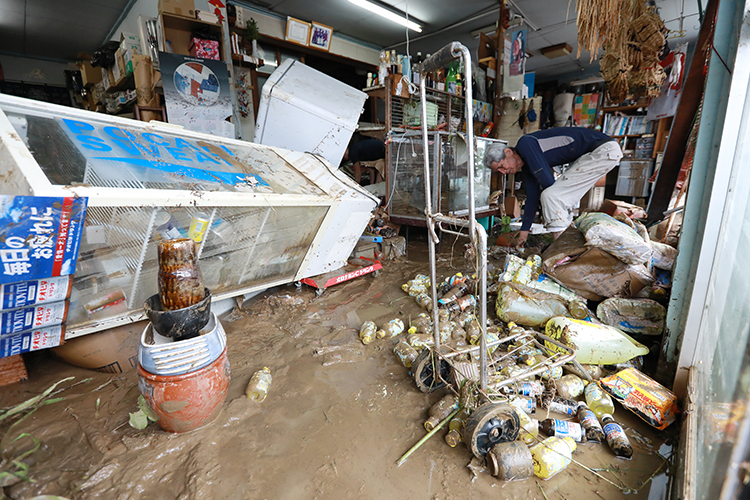 8月の九州北部豪雨にて、浸水した雑貨店を片づける店主（写真：時事通信フォト）