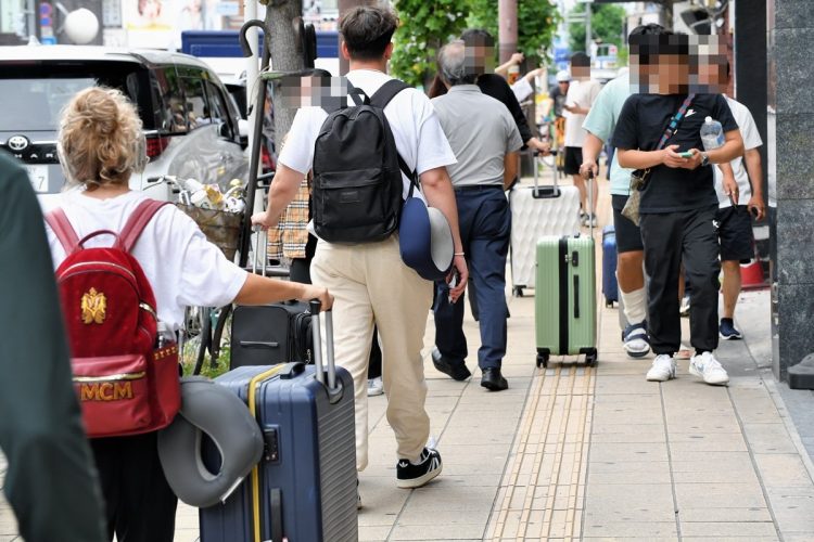 日本橋周辺で大きなスーツケースを引きながら歩く外国人観光客（撮影／杉原照夫）